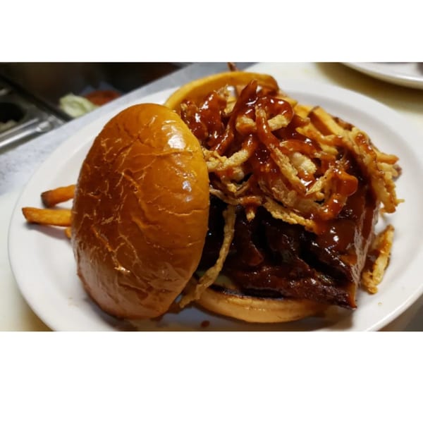Gio's Bar & Grill's BBQ burger with crispy fried onions, sauce, and a side of fries.