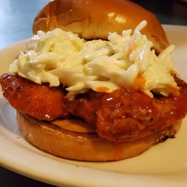 A Gio's Bar & Grill buffalo chicken sandwich with coleslaw on a toasted bun.